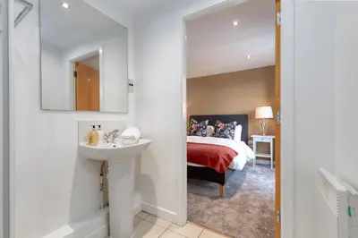 a bedroom with a bed and a sink and a mirror at SECC Hydro Clyde View Apartment in Glasgow