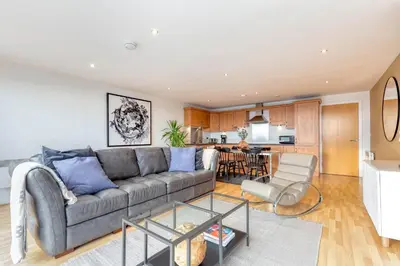 a living room with a couch and a kitchen at SECC Hydro Clyde View Apartment in Glasgow