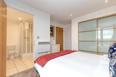a bedroom with a large white bed and a bathroom at SECC Hydro Clyde View Apartment in Glasgow