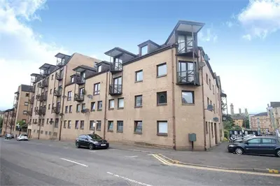 a large brick building with cars parked in front of it at Fresh, modern West End apartment beside Hydro in Glasgow
