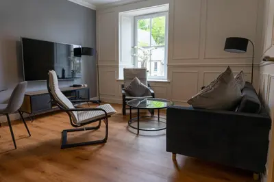 a living room with a couch and chairs and a television at Airds Apartments in Oban