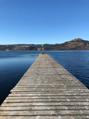a wooden pier in the middle of a body of water at The Moorings, overlooking Loch Fyne in Cairndow