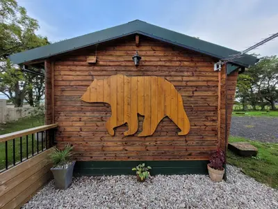 a wooden bear painted on the side of ashed at Cosy wood cabin in rural area near national park in Cumnock