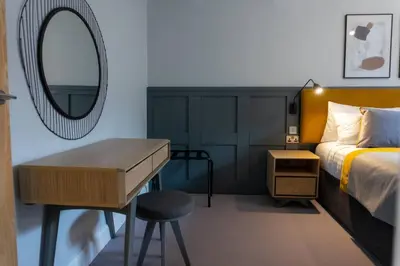 a bedroom with a bed and a desk and a mirror at Argyle Square Apartment in Oban