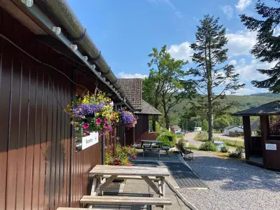 a picnic table with flowers hanging from the side of a building at Roam West in Fort William