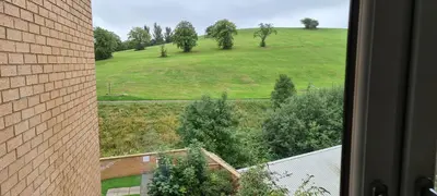 a view of a green field from a window at Espedair Apartment in Paisley