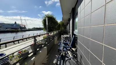 a balcony of a building with benches next to a river at Glasgow Harbour Clyde Waterfront Apartment in Glasgow