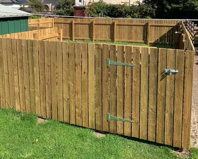 a wooden fence with two gates in the grass at Woodvale Flat, Renton, Loch Lomond in Renton