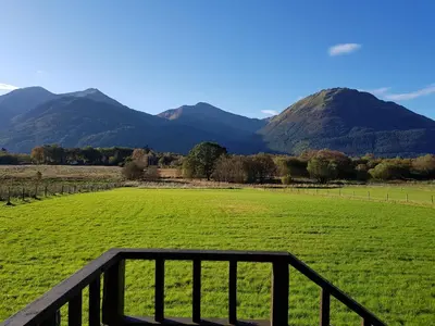 a view of a green field with mountains in the background at Oakview Chalet in Glencoe