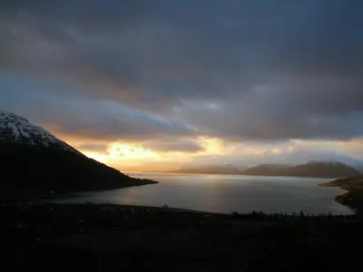 a sunset over a body of water with mountains at Oakview Chalet in Glencoe