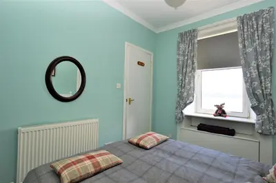 a bedroom with blue walls and a bed with a mirror at Arthur's Seat in Innellan