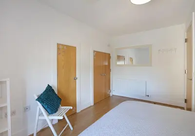 a white bedroom with a white bed and a chair at The Shandwick Place Residence No 2 in Edinburgh