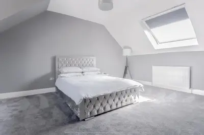 a bedroom with a bed in a white room at 4 Bed-Sleeps 8- Free Parking-Pets-Hot Tub in Kelty