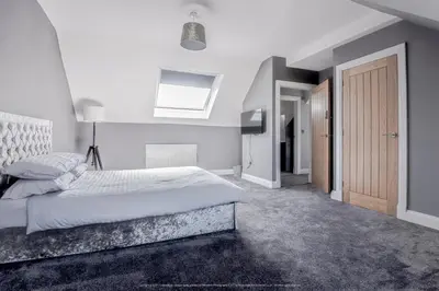 a white bedroom with a bed and a skylight at 4 Bed-Sleeps 8- Free Parking-Pets-Hot Tub in Kelty