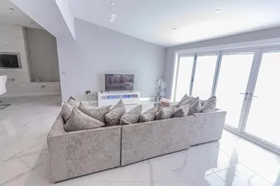 a large couch in a living room with large windows at 4 Bed-Sleeps 8- Free Parking-Pets-Hot Tub in Kelty