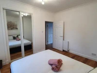a bedroom with a bed and a mirror at Glasgow Comfortable and Modern 3 Bedroom Mid Terraced Villa in Glasgow