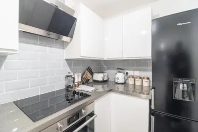 a kitchen with white cabinets and a black refrigerator at Luxury Glasgow Flat in the heart of the Westend in Glasgow