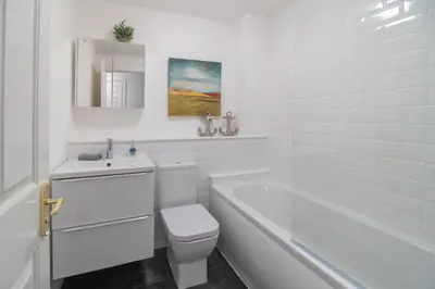 a white bathroom with a toilet and a tub and a sink at Luxury Glasgow Flat in the heart of the Westend in Glasgow