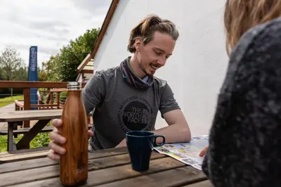 a man sitting at a table with a bottle of beer at Highland Basecamp in Lochaline