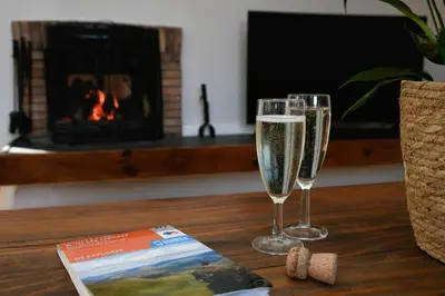 two glasses of champagne and a book on a table with a fireplace at Cologin in Oban