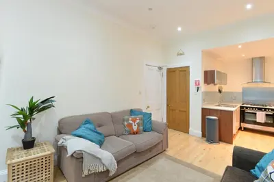 a living room with a couch and a kitchen at Home by The Meadows, close to City Centre in Edinburgh
