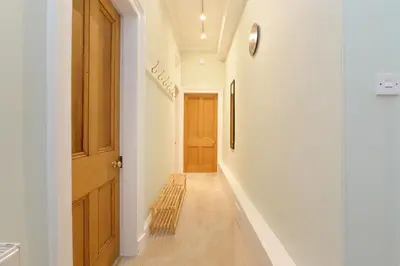 a hallway with white walls and a wooden door at Home by The Meadows, close to City Centre in Edinburgh