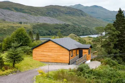 a wooden cabin on a hill with a road at Portnellan in Crianlarich