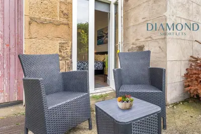 two chairs and a table in front of a store at Spacious 1 Bed Ground Floor Apartment with Garden in Edinburgh