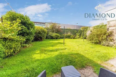a lawn in front of a building with a sign at Spacious 1 Bed Ground Floor Apartment with Garden in Edinburgh