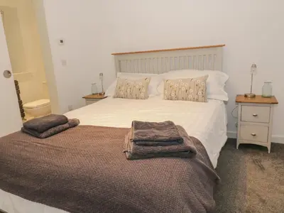 a bedroom with a large bed with towels on it at Dunaivon Cottage in Helensburgh