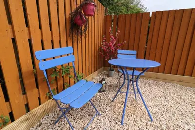 two blue chairs and a table in front of a fence at Signature - Culzean House in Newarthill