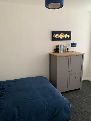 a bedroom with a bed and a desk with a blue blanket at The Cochno Flat, Clydebank in Dalmuir