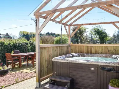 a wooden gazebo with a hot tub in a garden at Kinvara in Stranraer