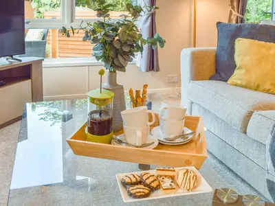 a living room with a coffee table with a tray of food at Riverside Lodge in Auchterarder