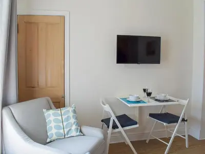 a living room with a chair and a table and a television at Osocozee in Millport