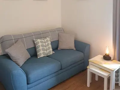 a blue couch in a living room with a table at Osocozee in Millport