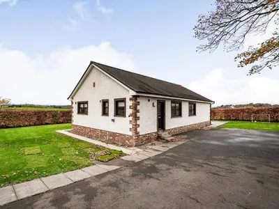 a small white house with a driveway at Rowan Muir in Springside