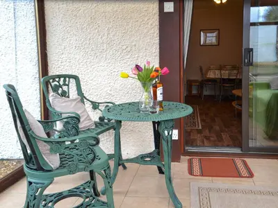 a green table with a vase of flowers and a chair at Ashley Cottage in Bowmore