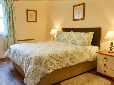 a bedroom with a bed and two lamps and a window at Ashley Cottage in Bowmore