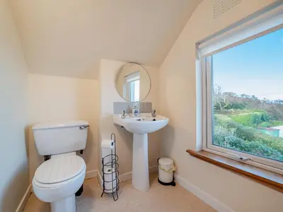 a bathroom with a toilet and a sink and a window at The Creagan in Corrie