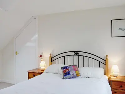 a bedroom with a large white bed with two lamps at Shore Cottage in Bellochantuy