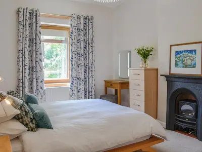 a bedroom with a bed and a fireplace at Lime Tree Cottage in Drumpark