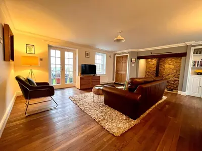 a living room with a leather couch and a television at Trossachs Barn & Cabin - boutique B&B in Port of Menteith