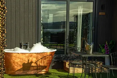a tub filled with snow sitting next to a table at Loch Lomond Waterfront Luxury Lodges in Balmaha