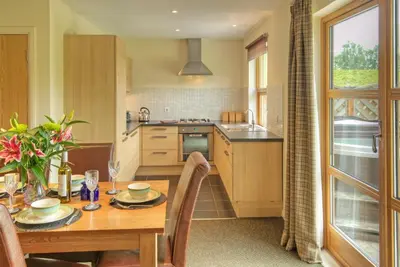 a kitchen with a wooden table and a dining room at Loch Lomond Waterfront Luxury Lodges in Balmaha