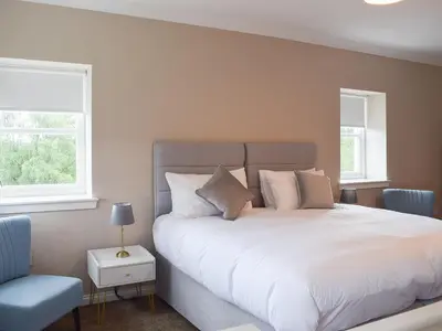 a bedroom with a large white bed and a chair at Fascadail-Uk34219 in Aberfoyle