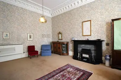 a living room with a fireplace and a red chair at Quirky, West End, Edinburgh House in Edinburgh