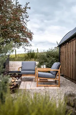 two chairs and a table on a patio at Luxury Glamping Pods - The Heft & The Hirsel in Glasgow