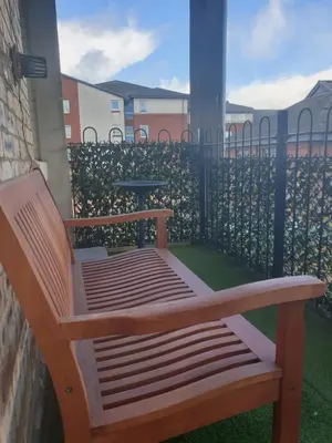 a wooden bench sitting on a balcony with a fence at Troon Beach Town Golf Apartment Troon Ayrshire in Troon