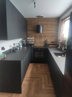 a kitchen with black cabinets and a wooden floor at Single bedroom in quiet neighbourhood in Mount Vernon